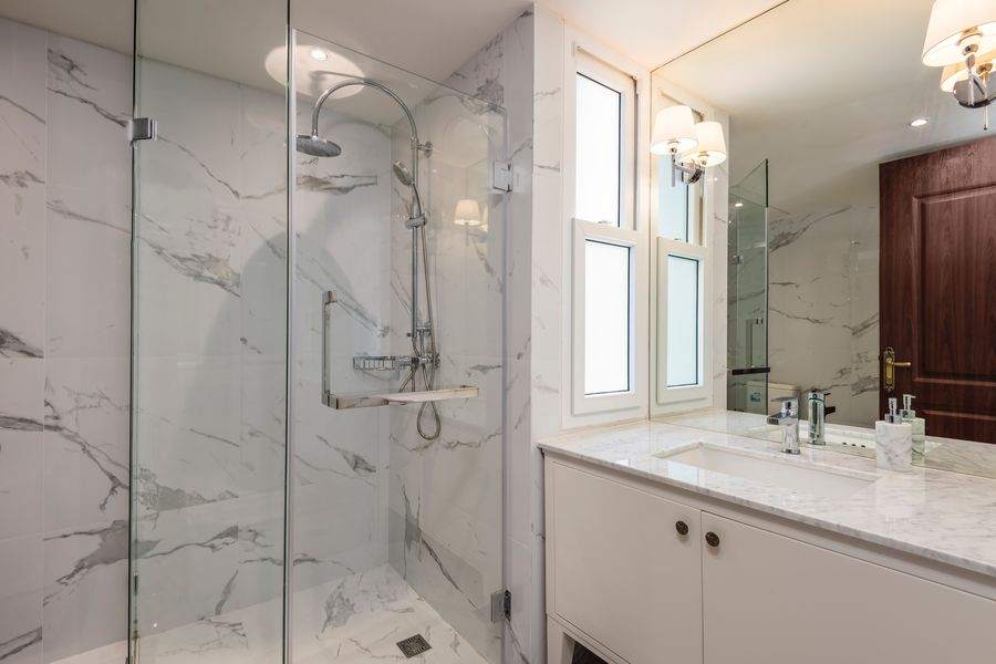 A marble bathroom with a walk in glass rain shower