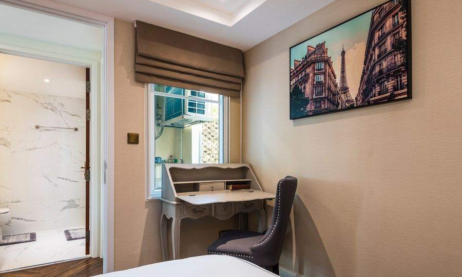 A bedroom with a writing desk and a framed print