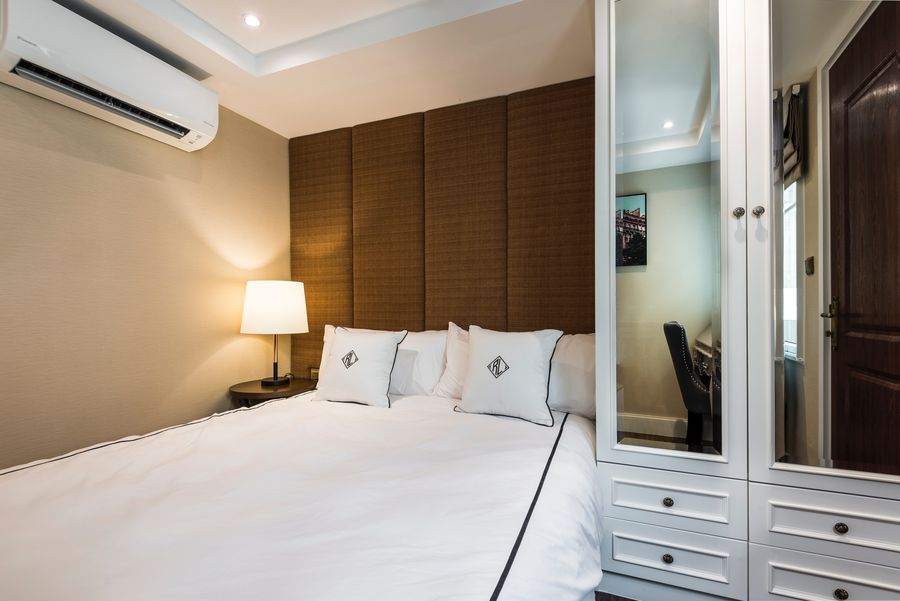 The master bedroom with a king bed and an upholstered headboard wall