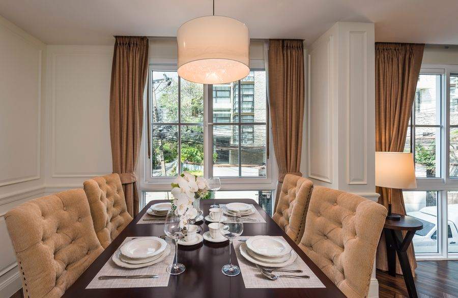 The dining room with panelled walls, a chandelier and a table for six at The Elite Thong Lor 25