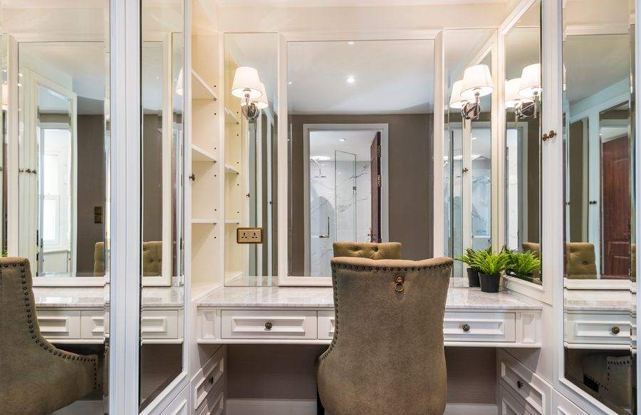 The dressing table in the walk in closet, with a marble top and sconce lighting