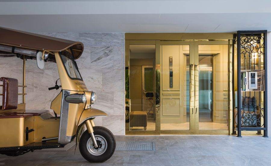 The entrance of The Elite at Thong Lor 25 on Soi Saeng Ngoen, with a gold tuk tuk parked beside the door