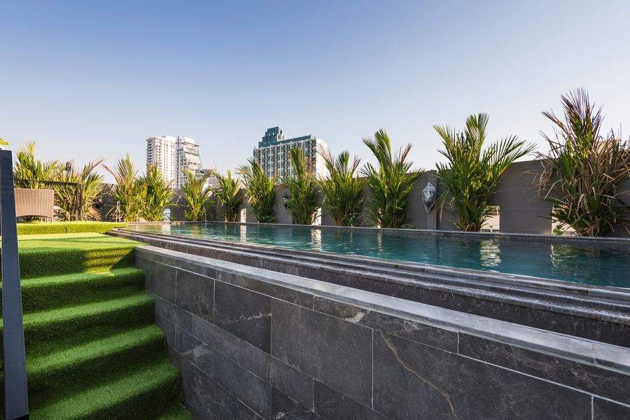 The rooftop pool and lawn at The Elite Thong Lor 25