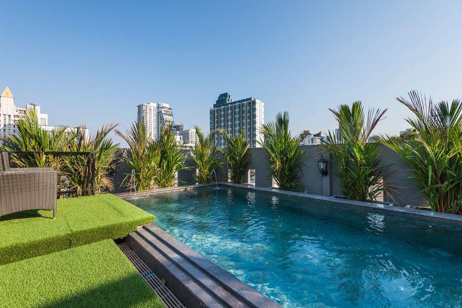 The rooftop pool with palms and the Bangkok skyline at The Elite Thong Lor 25
