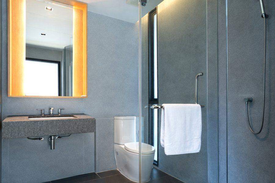 The second bathroom at The Elite @ Pattaya with a walk in rain shower behind glass and a warm lit mirror