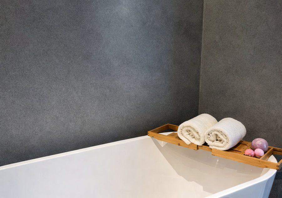 A freestanding bath at The Elite @ Pattaya with rolled white towels on a bamboo tray across it