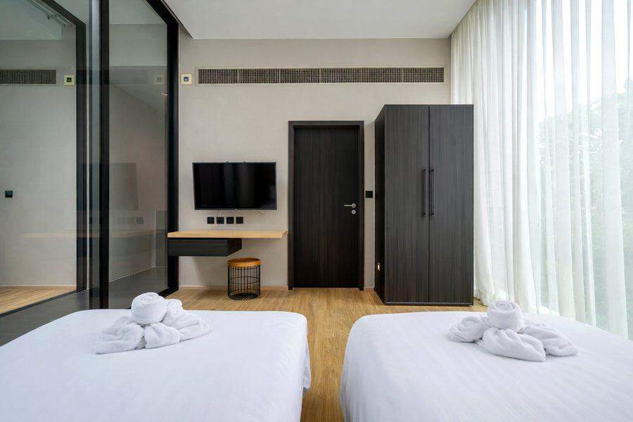 The second bedroom at The Elite @ Pattaya with two single beds, a desk and a wall mounted television