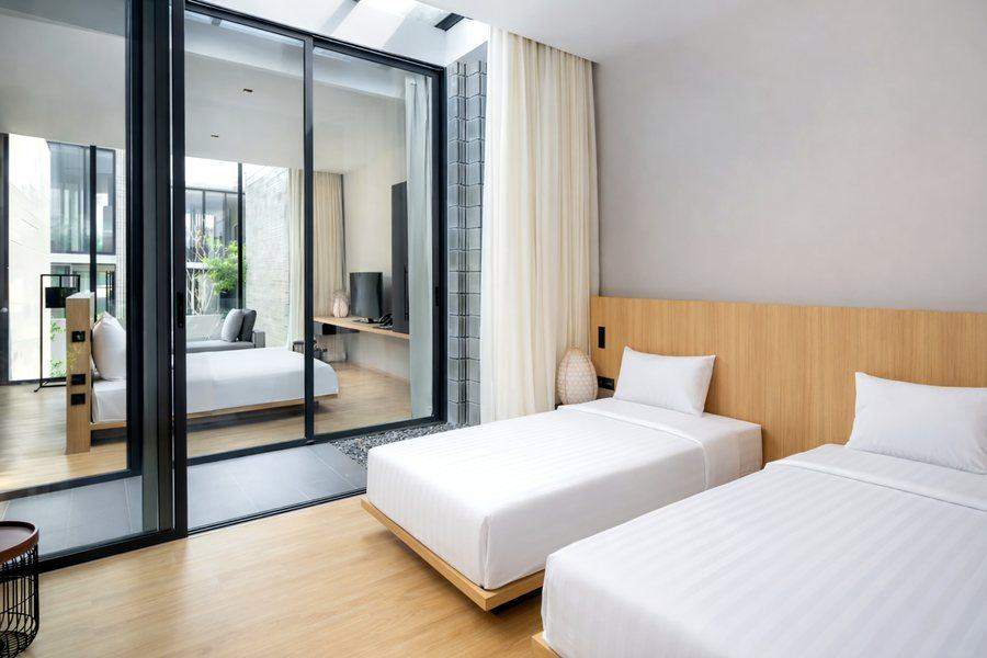 Two single beds at The Elite @ Pattaya beside a sliding glass wall onto the light well
