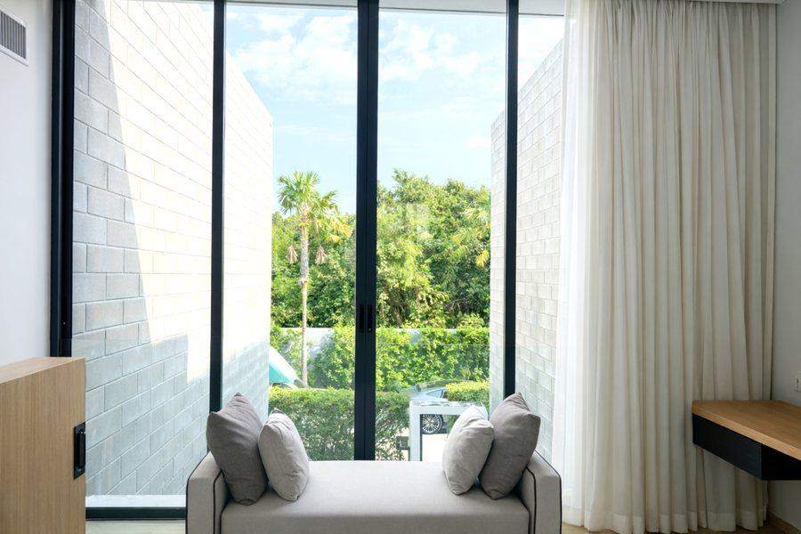 A window seat at The Elite @ Pattaya under full height glass, looking out to palms and greenery