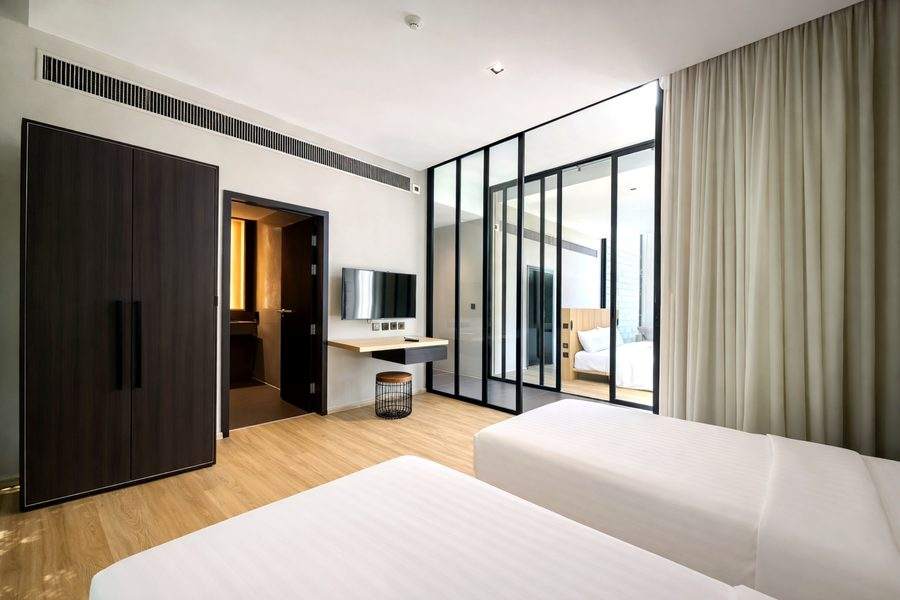 A bedroom at The Elite @ Pattaya with a full height dark wardrobe wall and a glass partition