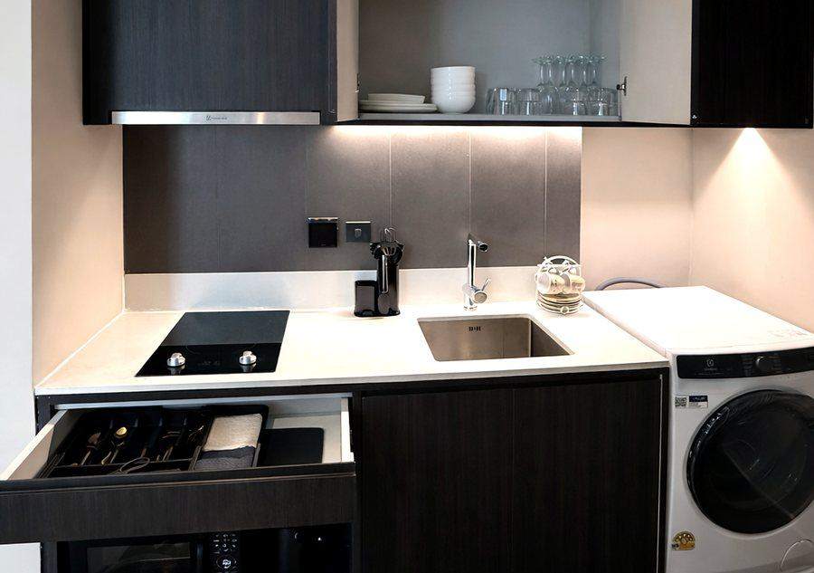 The kitchen at The Elite @ Pattaya with an induction hob, a sink, a microwave and a washing machine