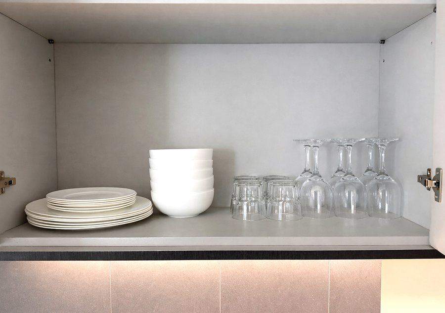 Plates, bowls, tumblers and wine glasses in the kitchen cupboard at The Elite @ Pattaya