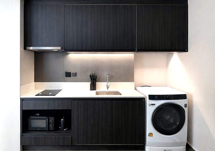 The kitchen at The Elite @ Pattaya from the side, with dark cabinets, extractor and washing machine