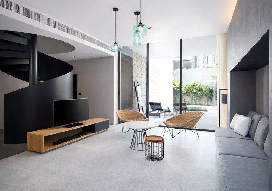 The living room at The Elite @ Pattaya, with a black spiral staircase, a sofa and full height glass sliding open to the private pool