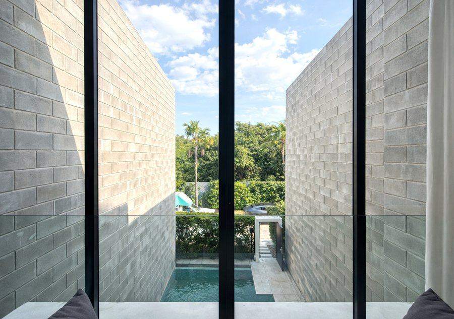The private pool at The Elite @ Pattaya seen from the upstairs bedroom window, with palms and greenery beyond the wall