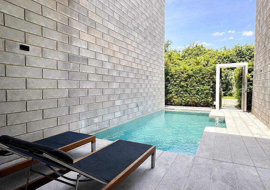 The private swimming pool at The Elite @ Pattaya with two sun loungers on a stone terrace between high garden walls