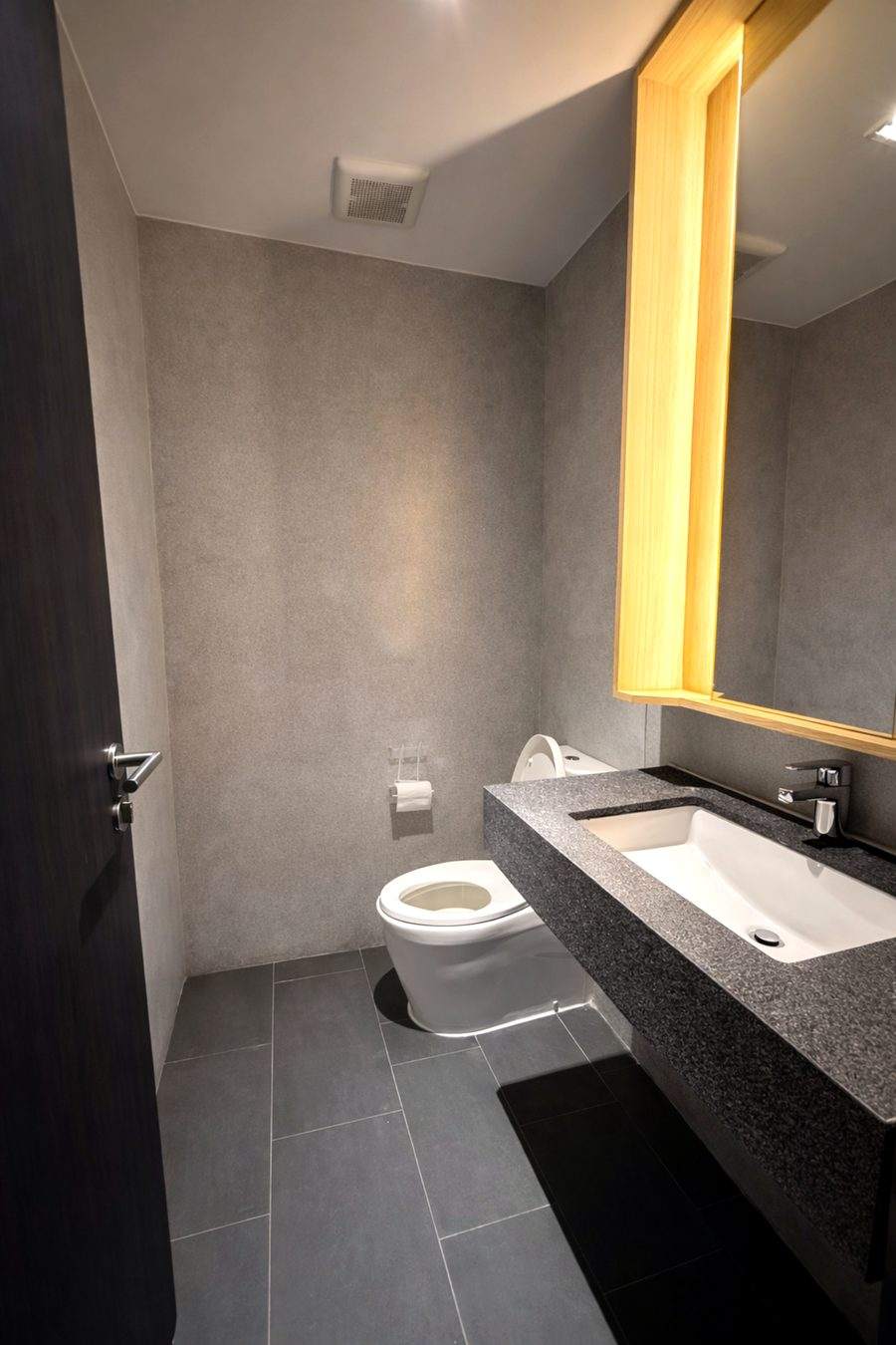The half bathroom at The Elite @ Pattaya with a stone vanity and an oak framed mirror
