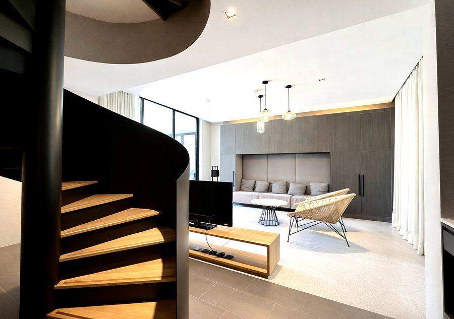 The oak treads of the spiral staircase at The Elite @ Pattaya with the living room beyond