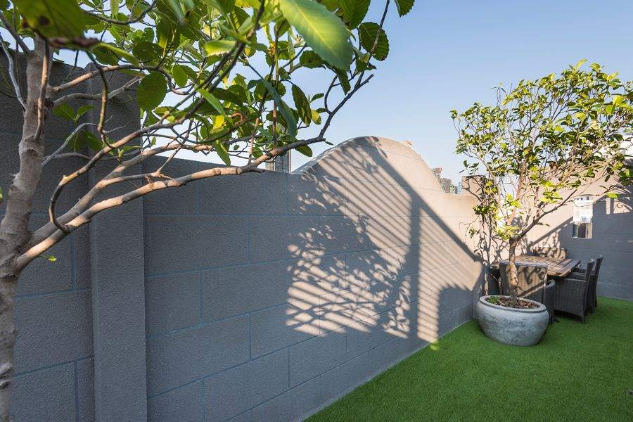 The roof garden with trees and a shaded table at The Elite Thong Lor 25